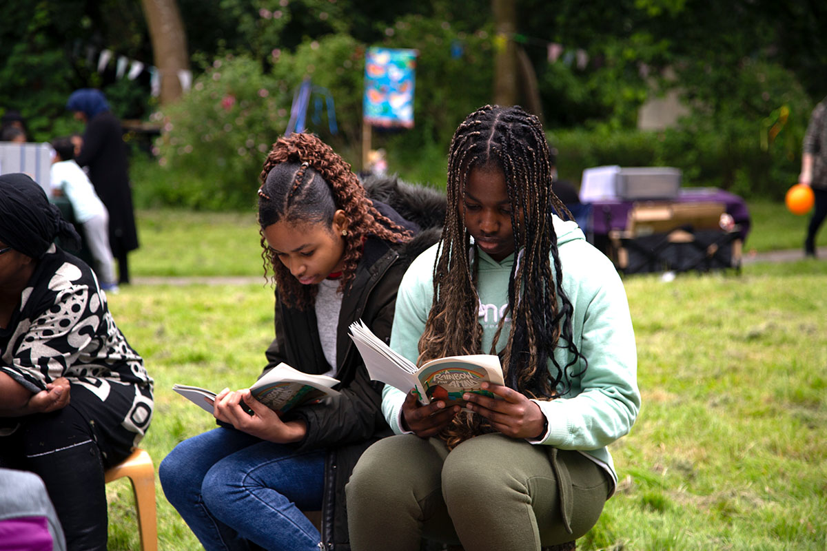 Two young people with long braids are reading books together.